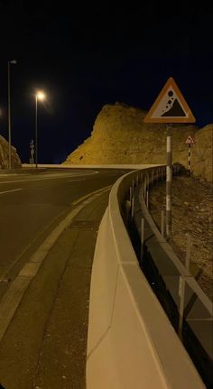 an empty road at night with a sign on the side