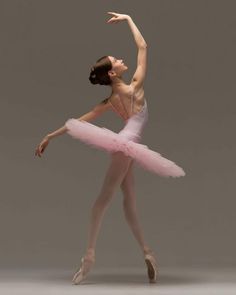 a ballerina in pink tutu and leotard with her arms stretched out