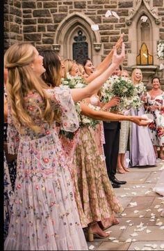 a bride and groom walking down the aisle with their wedding party throwing petals in the air