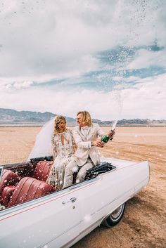 a bride and groom sitting in the back of a convertible car on their wedding day