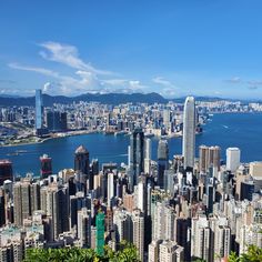 an aerial view of a large city and the ocean with mountains in the background on a sunny day