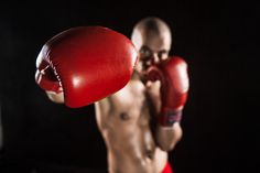 a shirtless man wearing red boxing gloves