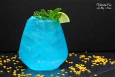 a blue drink with lime and mint garnish