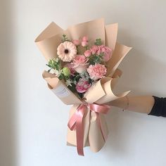 a bouquet of flowers is wrapped in brown paper with pink and white flowers on it