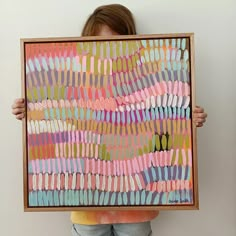 a person holding up a painting with different colors