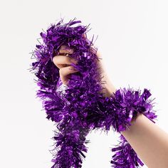 two hands are holding purple tinsel