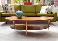 a living room with a green couch and coffee table in front of large windows,