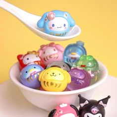 a bowl filled with lots of different colored plastic animals on top of a white table