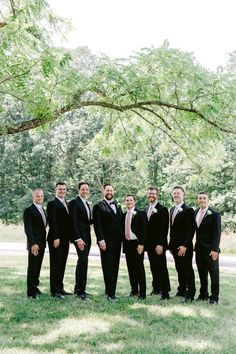 a group of men standing next to each other in front of a tree