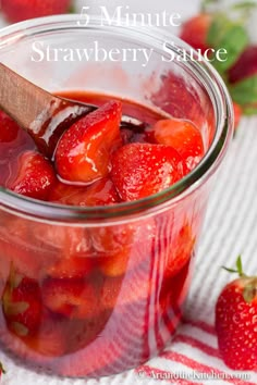 a jar filled with sliced strawberries on top of a white and red table cloth