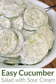 cucumber salad with sour cream and herbs in a white bowl on a wooden table