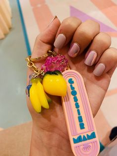 a person holding a yellow and pink keychain with some fruit on top of it