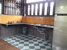 an empty kitchen with green and white checkered flooring on the walls, windows, and sink