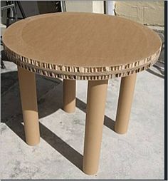 a round table made out of cardboard sitting on concrete with no one around it,