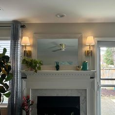 a living room with a fire place next to a window and potted plants on the mantle