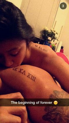 a woman laying on top of a bed with her arm tattoo reading the beginning of forever