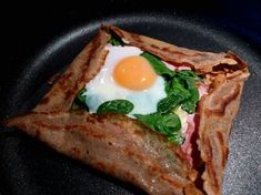 an egg and spinach wrap on a black plate