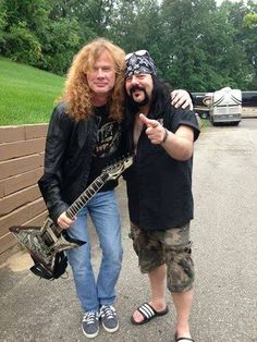 two men standing next to each other holding guitars