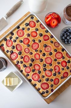 a pan filled with blueberries and strawberries on top of a wooden cutting board