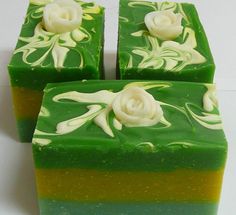 three pieces of green and yellow soap with white flowers on them, sitting next to each other