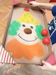 a cardboard box with a drawing of a clown on it and a red ball in the middle