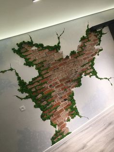 a brick wall with green vines growing on it in an empty room next to a door