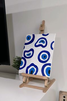 an easel with a blue and white painting on it next to a computer monitor