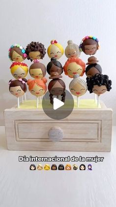 a bunch of little dolls sitting on top of a wooden box next to each other