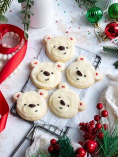 cookies decorated to look like teddy bears on a cooling rack with christmas decorations around them