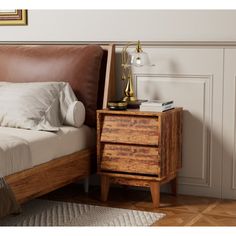 a bed sitting next to a night stand on top of a wooden floor