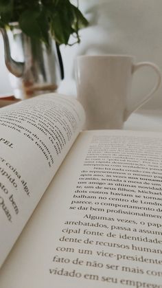 an open book sitting on top of a table next to a cup