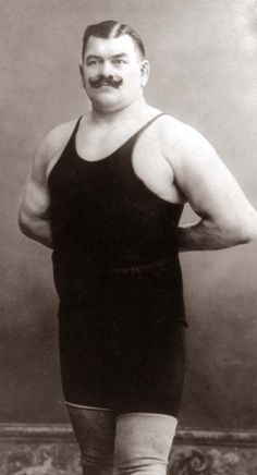 an old photo of a man with a moustache on his face and hands behind his back