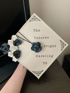 a hand holding a graduation cap with flowers on it that says the future is bright dazzleling us