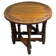 a round wooden table with an intricate design on it's top and legs, against a white background