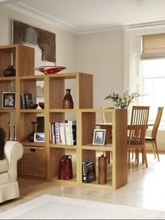 a living room filled with furniture and bookshelves next to a white rug on top of a hard wood floor