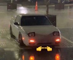 a white car driving down a street in the rain