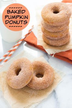 baked pumpkin donuts stacked on top of each other next to a glass of milk