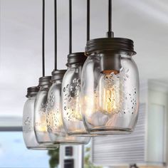 mason jar chandelier with lights hanging from it's sides in a kitchen