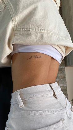 the back of a woman's stomach with her name tattoo on it