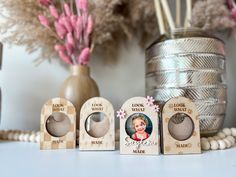 three wooden magnets are sitting next to each other on a table with flowers in the background