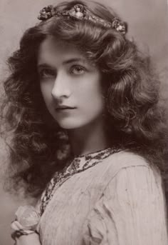 an old black and white photo of a woman with long hair wearing a headband