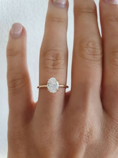 a woman's hand with a diamond ring on top of her finger and the other hand holding an engagement ring