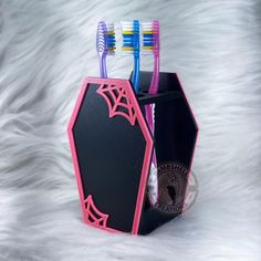 two toothbrushes in a holder on top of white fur covered surface with black and pink accents