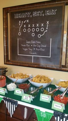 a football party with snacks on the buffet table and a chalkboard sign above it