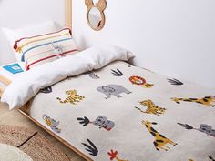 the bed is made up with colorful animals on it