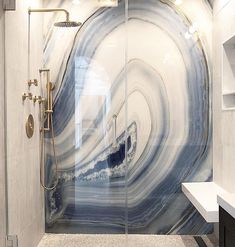 a white and blue marble bathroom with glass shower doors