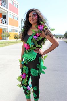 a woman in black and green outfit with flowers on her body posing for the camera