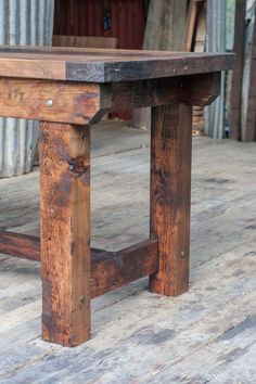 an old wooden table sitting on top of a wooden floor in front of a building