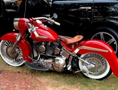 a red motorcycle parked next to a black car