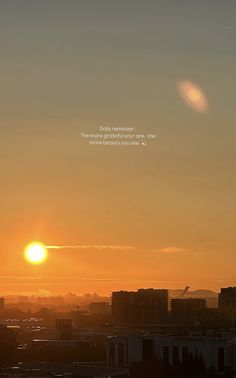 the sun is setting over a city with buildings in the foreground and an airplane flying overhead